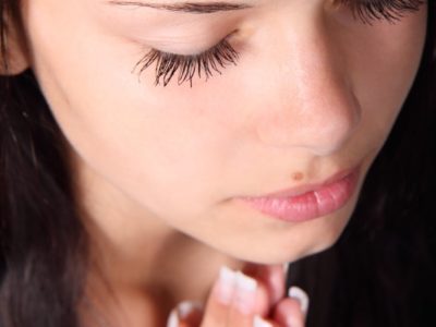 Woman with closed eyes and clasped hands beneath chin